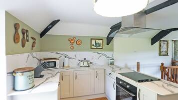 A compact kitchen with white cabinets, a microwave, a toaster, and a stove.