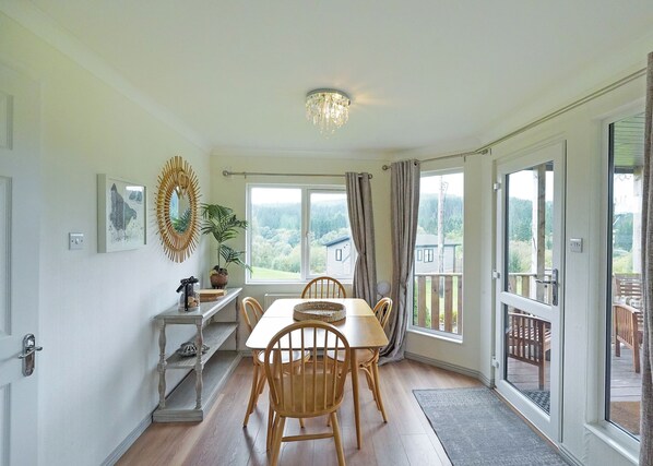 A dining area with a table and chairs, a decorative mirror, and a view of the outdoors through large windows. - 2 bedroom accommodation in Kielder (Kielder)