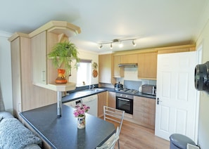 A compact kitchen with a dining area, featuring a built-in oven, microwave, and a small refrigerator. - 2 bedroom accommodation in Kielder (Kielder)