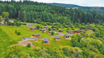 A rural area with multiple small cabins surrounded by lush greenery and a forested hill in the background.