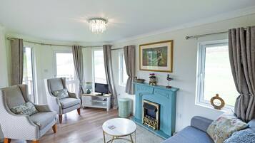 A living room with a fireplace, two sofas, a television, and a dining area.