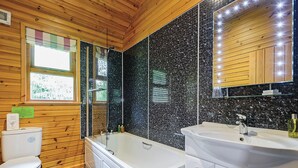 A bathroom with a bathtub, a toilet, and a sink. - Lodge with one king-size double with en suite bathroom with shower. (Kilcot, Newent)