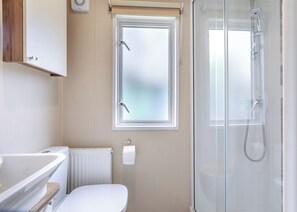A bathroom with a toilet, a bathtub, a shower, and a frosted window.