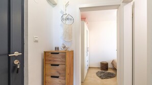 A hallway with a wooden cabinet, a wall-mounted macrame decoration, and a small rug on the floor. - Gorgeous apartment in Labin with WiFi (Labin)