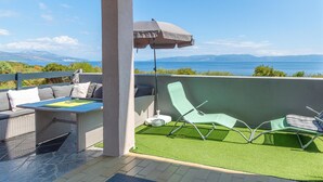 A patio with a table and chairs, a green lawn, and a view of the sea. - Gorgeous apartment in Labin with WiFi (Labin)