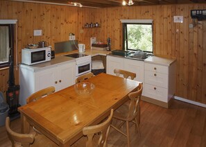 Eine Küche mit Holzwänden, weißen Schränken, einem Holztisch und einem Fenster, das für natürliches Licht sorgt.