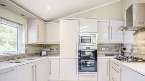 Cuina moderna amb armaris blancs, microones integrat, forn i fogó de gas.