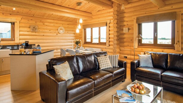 A log cabin interior with a living area, kitchen, and dining space. - One double with en suite shower and one twin. (Laxfield, Nr Woodbridge)