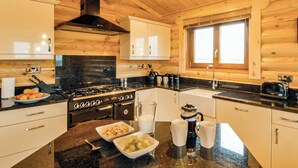 A modern kitchen with wooden walls, a stove, and a window. - One double with en suite shower and one twin. (Laxfield, Nr Woodbridge)