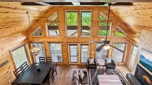 A wooden cabin interior with a dining area, seating, and a fireplace.