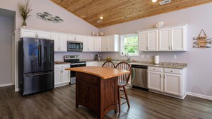 A kitchen with white cabinets, a wooden ceiling, and a central island with chairs. - RIVER FRONT HOME AMAZING VEIWS AND HOT TUB (Shenandoah)