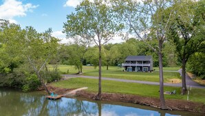 A house with a dock by a calm lake, surrounded by trees and a well-maintained lawn. - RIVER FRONT HOME AMAZING VEIWS AND HOT TUB (Shenandoah)