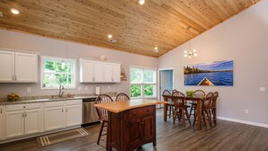 A spacious kitchen with wooden cabinets, a large island, and a dining area with chairs. - RIVER FRONT HOME AMAZING VEIWS AND HOT TUB (Shenandoah)