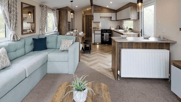 Una sala de estar moderna con un sofá, una mesa de centro con una planta, y una zona de cocina con estufa y fregadero.