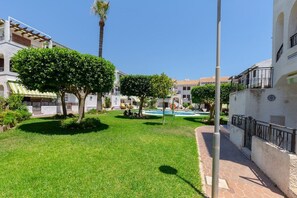 Un patio con piscina, rodeado de edificios con balcones y un cielo azul despejado.
