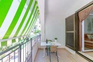Een balkon met een witte tafel, stoelen en een bloempot.