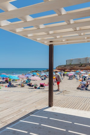 Une plage avec une terrasse en bois et des parasols.