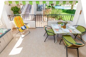 Un balcón con una mesa de comedor lista para cuatro personas, rodeada de sillas.