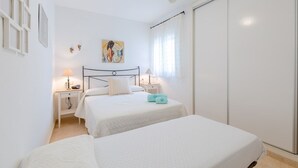 A bedroom with two beds, a ceiling fan, a painting on the wall, and a window with curtains. - Flamingo Coast by Fidalsa (La Zenia)