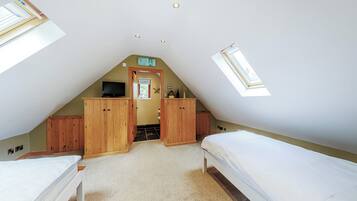 Ein Schlafzimmer mit zwei Betten, Holzschränken, einem Fernseher und einem Oberlicht.