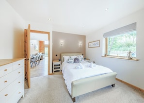 A bedroom with a bed, bedside tables, a window, and a view of the outdoors.