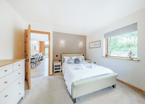 A bedroom with a bed, bedside tables, a window, and a view of the outdoors.