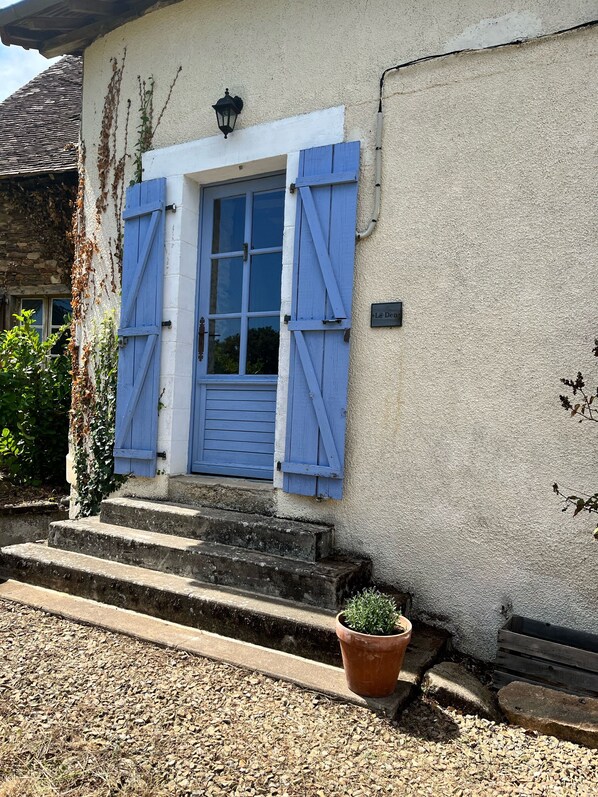A building with a white exterior, a blue door, and blue shutters. There is a small potted plant on the steps. - Countryside Retreat (Jumilhac-le-Grand)