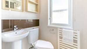 A bathroom with a sink, toilet, and towel rack. - Luxurious holiday home. (Looe)