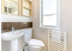 A bathroom with a sink, toilet, and towel rack.
