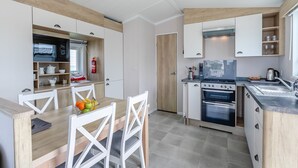 A modern kitchen with white cabinetry, a dining table with chairs, and a built-in oven.