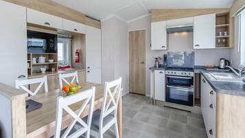 A modern kitchen with white cabinetry, a dining table with chairs, and a built-in oven.