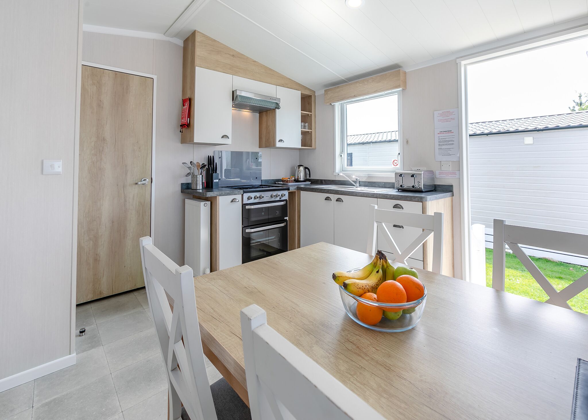 Une cuisine moderne avec des meubles blancs, un plan de travail en bois et une table à manger agrémentée d’un panier de fruits.