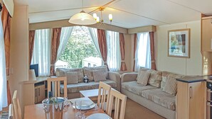 A cozy living area with a dining table set for four, a sofa, and a kitchenette.