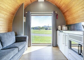 A cozy interior with a sofa, kitchenette, and a view of a grassy field.