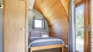 Una camera da letto con soffitto in legno, un letto, una finestra con tende e una porta.