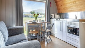 Un ambiente accogliente con tavolo da pranzo, sedie, divano, cucina dotata di fornello e vista sull'esterno.