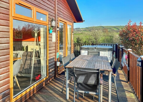 A wooden cabin with a deck, a table, and chairs.