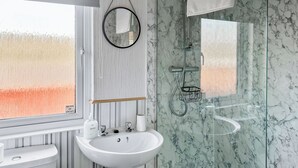 A bathroom with a white sink, a toilet, a shower with a glass enclosure, and a mirror. - Country Lodge Six Spa (Tintagel)