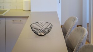 Cozinha moderna com armários brancos, bancada branca e luminária pendente.