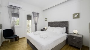 Quarto com cama grande, cadeira, mesa de cabeceira e criado-mudo.