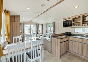 A modern kitchen with wooden cabinets, a microwave, and a window overlooking a residential area.