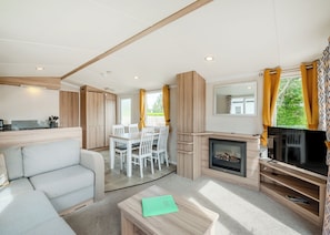 A modern, well-lit living room with a sofa, dining table, and TV area. - Comfortable caravan with one double with en suite with toilet, and one twin. (Cawood, Selby)