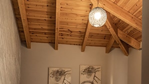 A bedroom with a wooden ceiling, a bed with white linens, two wall-mounted artworks, and a nightstand. - Angel Saranda Palace (Sarandë)