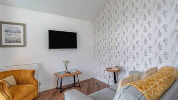 Un salon avec un canapé, une table basse, un téléviseur et un papier peint à motifs.