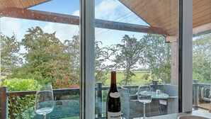 A dining area with a table set for two, a bottle of wine, and a view of the outdoors.
