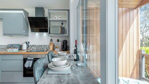 A modern kitchen with a large window, a built-in microwave, and a dining area with a hot tub visible through the window.