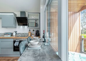 Moderni keittiö, jossa on suuri ikkuna, sisäänrakennettu mikroaaltouuni ja ruokailutila, josta näkyy poreallas ikkunan läpi.