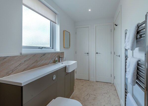 Ein Badezimmer mit Marmorplatte, Waschbecken, Spiegel und Handtuchhalter.