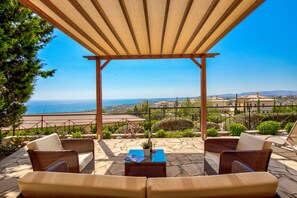 A covered outdoor seating area with wicker furniture and a view of the sea. - Apartment CC02 - Incredible Sea Views (Kouklia)