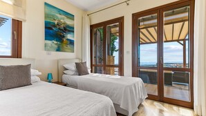 Habitación de hotel con dos camas, un ventanal con vistas y un cuadro en la pared.